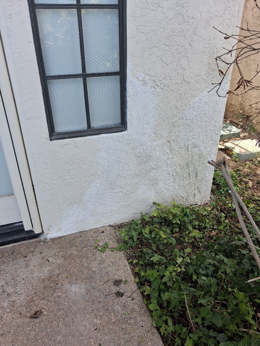 Documented AWC stucco repair-stage surface below an exterior window, before any separately scoped painting